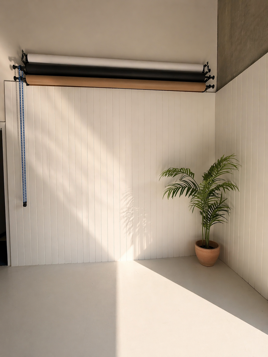 Wall-mounted backdrop system beside a white panelled shooting wall at 72 Studios photography studio